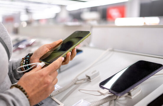 Woman testing new smartphone at store display counter