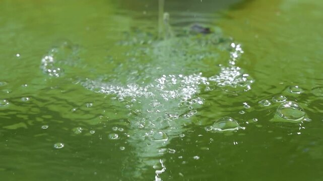 Green water surface with bubbles in slow motion