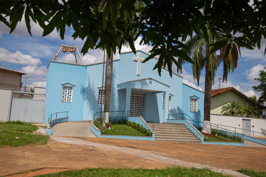 Par&oacute;quia Nossa Senhora da Guia com detalhe de galhos de &aacute;rvore na frente e c&eacute;u nublado ao fundo.
