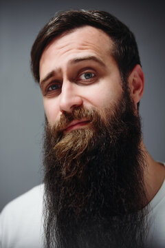 Portrait of bearded man looking at camera with soft lighting and sceptical expression.