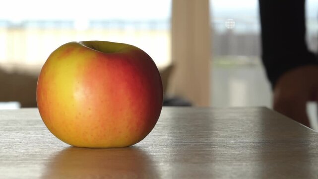 Person taking and returning bitten apple on table