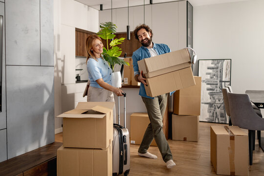 Couple carrying moving boxes into their new apartment during a home move