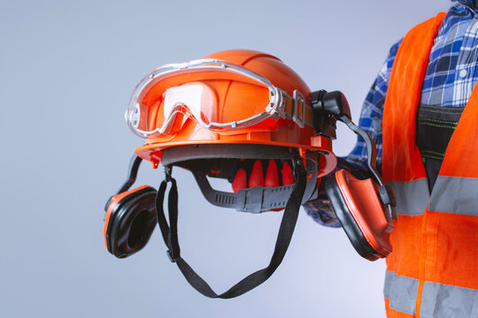 Construction worker with personal protective equipment safety helmet, protective goggles and earmuffs. Concept Industrial safety gear for construction and workplace protection on a light background.
