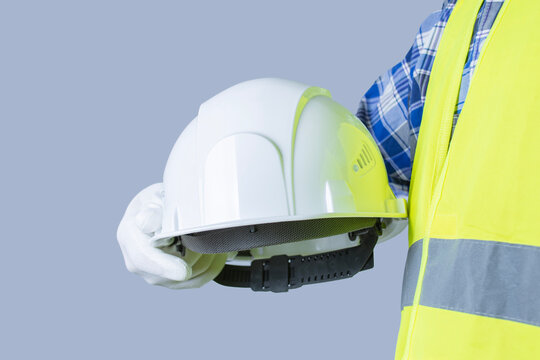 Construction worker in high visibility vest holding white safety helmet with copy space. Industrial safety equipment, PPE or workplace protection concept.