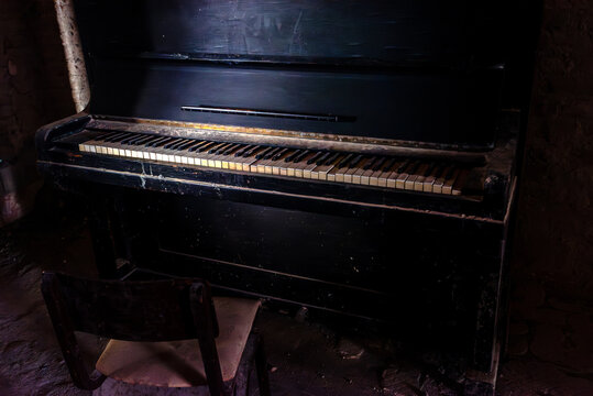 Old broken piano and chair in abandoned ruined mansion. Haunted house interior