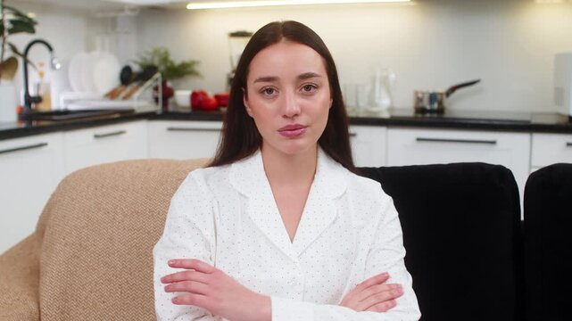 Young woman at home raises index finger says no firm look refuses idea blocks request shows disapproval. Caucasian girl on sofa leans back shakes head calm strict gesture clear message not agree stop.