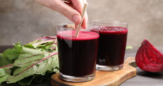 Woman taking beetroot smoothie in glass at wooden table, closeup