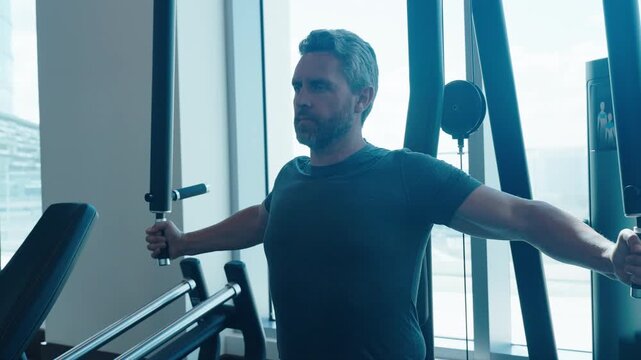 Strong sportsman training at pec fly machine in gym. Sporty man training on chest fly machine in gym. Chest fly on pec deck machine. Pectoralis muscles workout. Chest fly machine workout