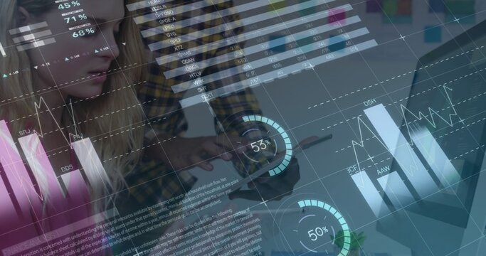 Reviewing coworkers leaning at desk, wearing plaid shirt, using tablet viewing analytics