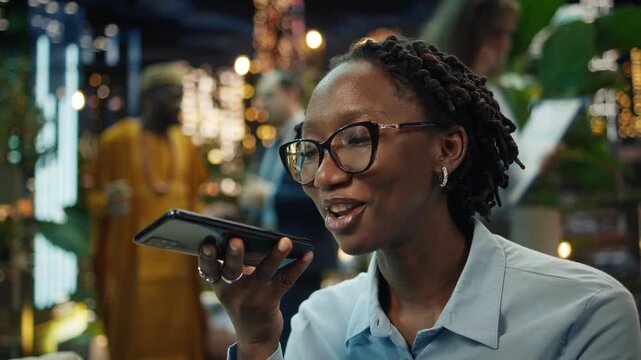 businesswoman records a smartphone voice message in a rooftop lounge, preparing audio notes and client feedback for a professional meeting or business call.