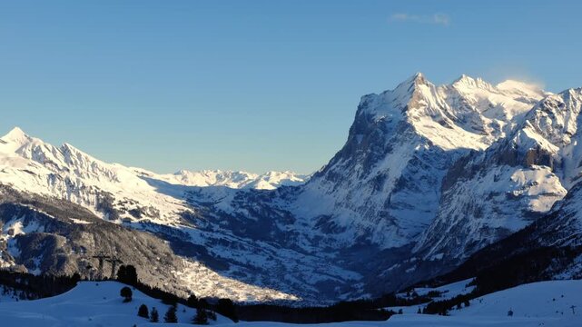 Beautiful Panoramic View over Snowcapped Mountain Peak Wetterhorn 3692 Meters High and Valley in the Swiss Alps in a Sunny Winter Day with Blue Sky in Grindelwald, Bernese Oberland, Bern Canton, Swit