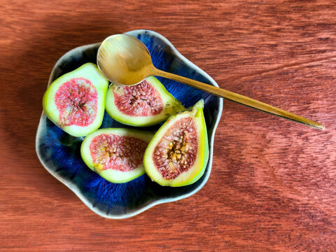 Sliced fresh raw organic desert king figs in dark blue dish ready to eat in top view