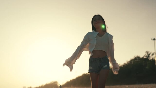 Summer beach freedom Asian woman walking at sunset with arms outstretched