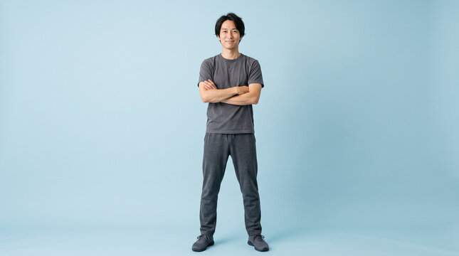 白背景で腕を組んで自信に満ちた表情のスリムな体型の30代日本人男性：筋トレ・ボディメイクの成果のイメージ