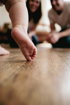 Toddler taking first steps on wooden floor