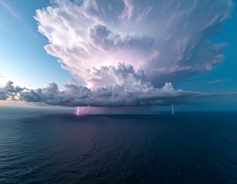 Un immense cumulonimbus orageux domine le ciel au-dessus d'une mer calme o&ugrave; un petit bateau blanc contraste avec les &eacute;clairs internes et les teintes violettes