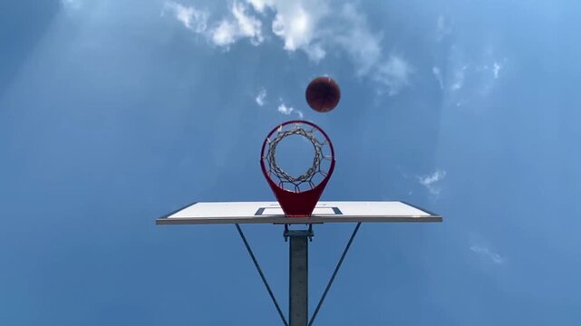 Orange basketball flies to the basket with net and bounces back from the rim missing the winning points at a basketball game missed ball throw in basket.