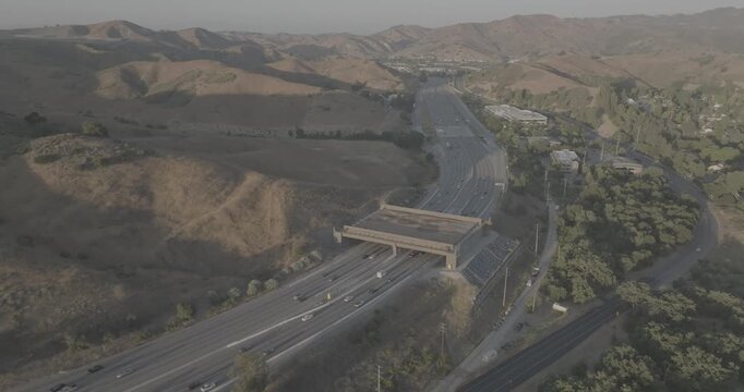 Aerial View of a Wildlife Crossing Bridge Over a Highway Between Dry Hills