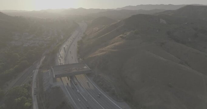 Aerial Drift Over a Highway Wildlife Crossing in Sunlit Dry Hills