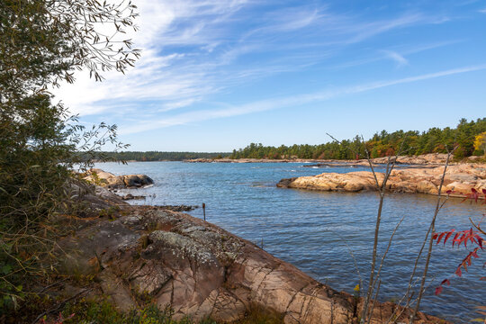Tranquil scene of Georgian Bay's rocky shoreline and greenery along Killarney's Lighthouse Trail, Ontario.
