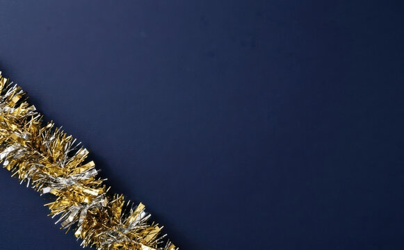 Gold and silver Christmas tinsel garland on deep blue background festive flatlay background