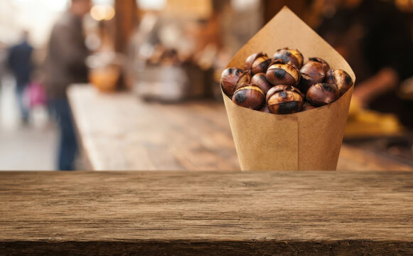 Roasted chestnuts in a paper cone on a wooden table at a winter street market concept