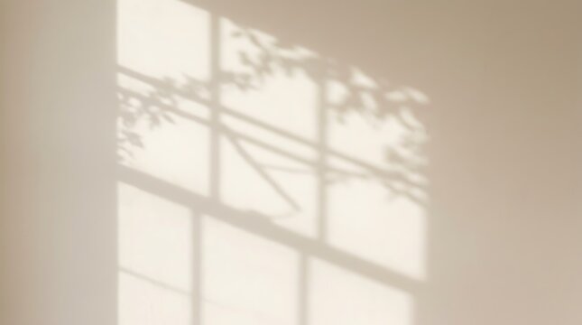 Soft window light shadow with tree leaves cast on a beige wall interior