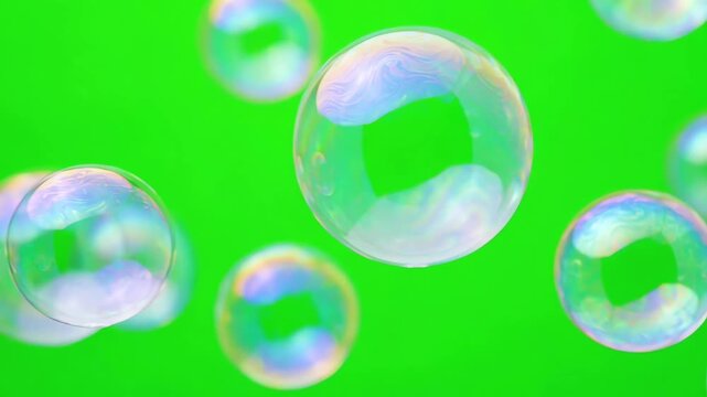 Large iridescent pastel bubbles drifting across a chroma key green backdrop with smooth shimmering motion