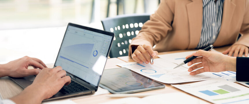 Panoramic Close Up of Business People Hands Pointing Pen at Financial Documents and Laptop in Meeting