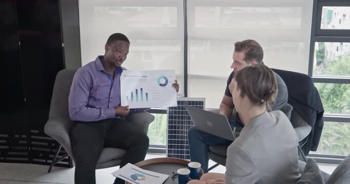 Businessman presenting growth chart to colleagues in casual office meeting