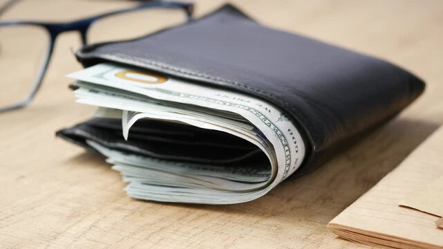Folded newspaper tucked inside a black wallet on a wooden table