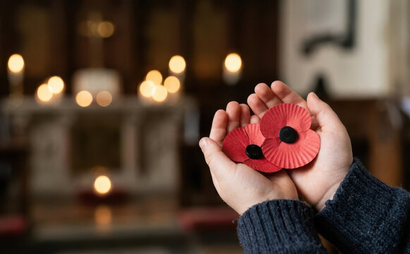 Child holding red remembrance poppies in church hands offering tribute for fallen soldiers