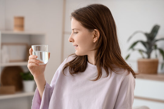 Hydration and wellness, young woman drinking a glass of fresh water for healthy lifestyle and daily self care routine in a bright home interior