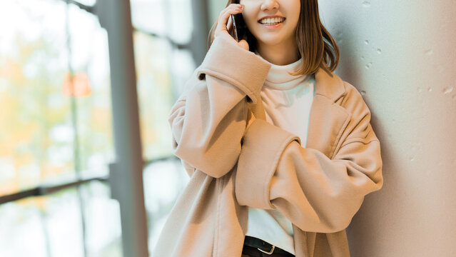 スマートフォンで通話をするコートを着た女性
