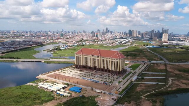 Aerial view of a large police administration complex south of Phnom Penh, Cambodia, surrounded by wetlands, new roads and expanding urban development with the skyline beyond.