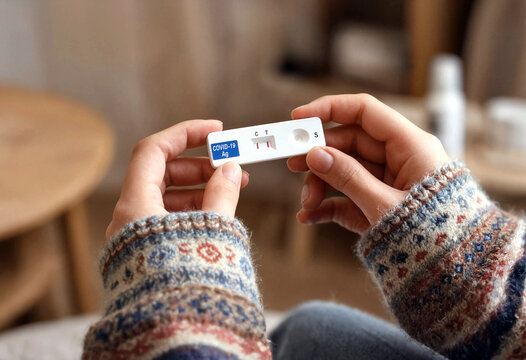 Person holding COVID19 antigen rapid test showing positive result at home with visible control and test lines