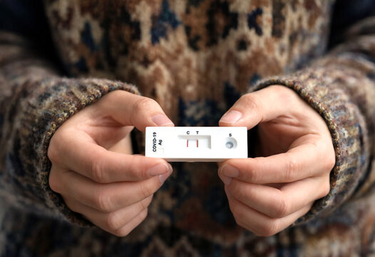 Person holding covid nineteen rapid antibody test showing positive result lines clearly visible
