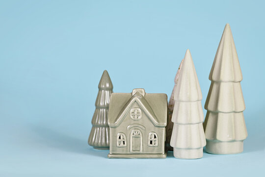Light green ceramic Christmas trees and house on blue background
