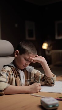 Tired thoughtful boy doing homework with head resting on hand. Fatigue concentration studying academic stress concept
