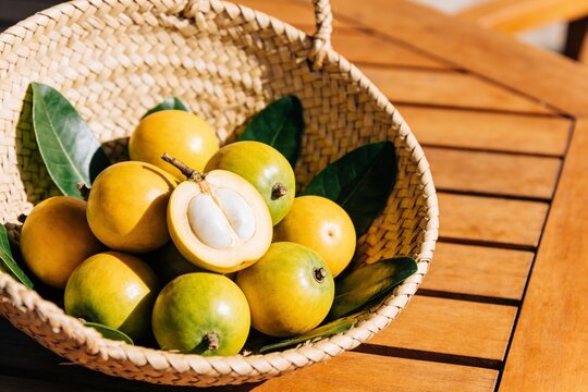 Fresh marula fruit with leaves in a woven basket one cut open