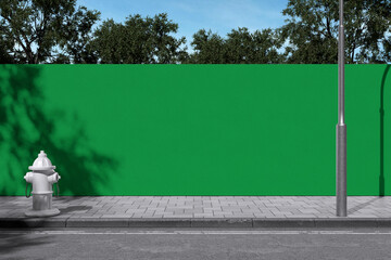 Green screen blank hoarding wall along city sidewalk with fire hydrant and street lamp mockup © Rielismee