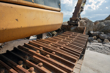 Close-up of heavy excavator tracks and boom on a seaside construction site. © Janis Smits