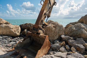 Close-up of heavy excavator tracks and boom on a seaside construction site. © Janis Smits