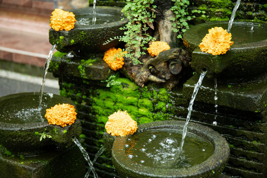 Water cascades from stone fountains surrounded by lush greenery