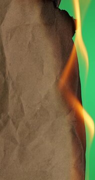 Burning Wrapping Paper with Green Screen Background. Brown wrapping paper burns completely against green screen curling into charred fragments. 