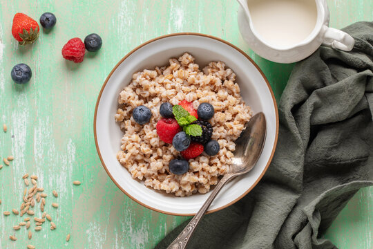 Pearl barley porridge with berries in a bowl on the table. Healthy breakfast. Top view
