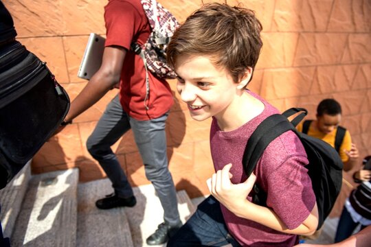 Group of students with backpacks climbing stairs outdoors.