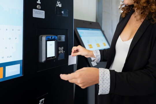 White woman collecting ticket from public transport ticket machine