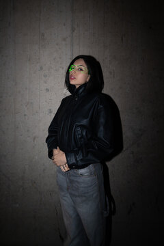 Hispanic woman wearing black leather jacket and green visor glasses