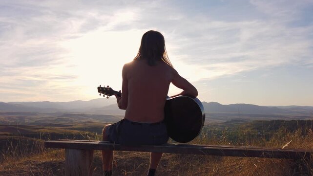  Slow motion view of musician playing guitar on in mountains during sunset